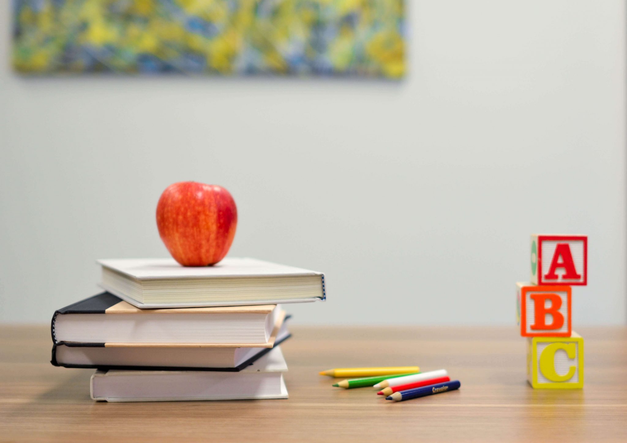 Bücher, Stifte, Buchstaben und ein Apfel liegen auf einem Schreibtisch
